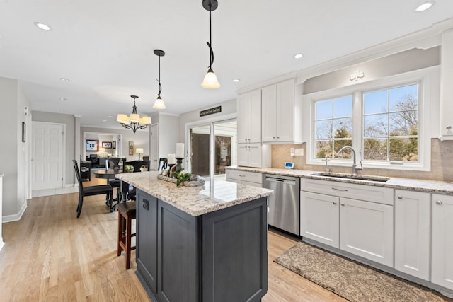 kitchen featuring tasteful backsplash, white cabinets, a kitchen island, a sink, and dishwasher