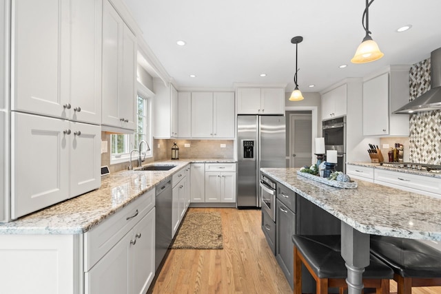 kitchen with a sink, stainless steel appliances, light wood-style floors, white cabinetry, and backsplash