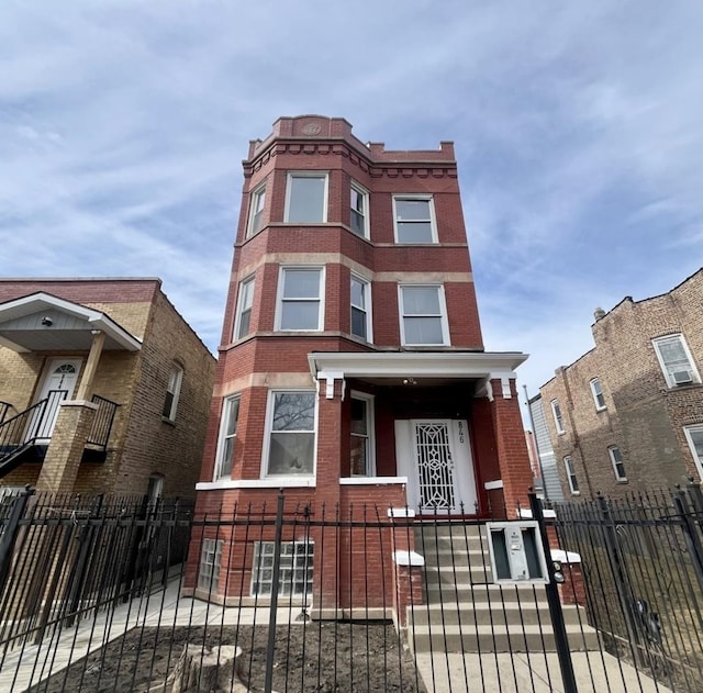 townhome / multi-family property with a fenced front yard, a gate, and brick siding