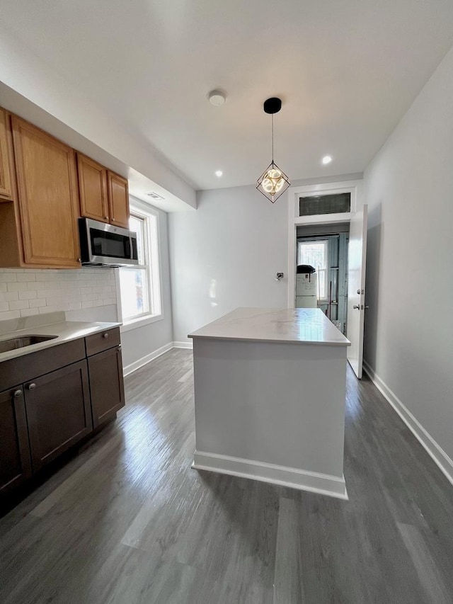 kitchen featuring dark wood-style floors, a healthy amount of sunlight, stainless steel microwave, and decorative backsplash