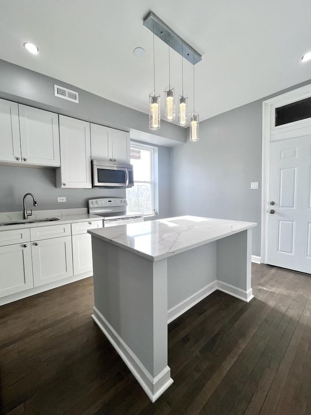 kitchen featuring visible vents, white cabinets, white range with electric cooktop, stainless steel microwave, and a sink