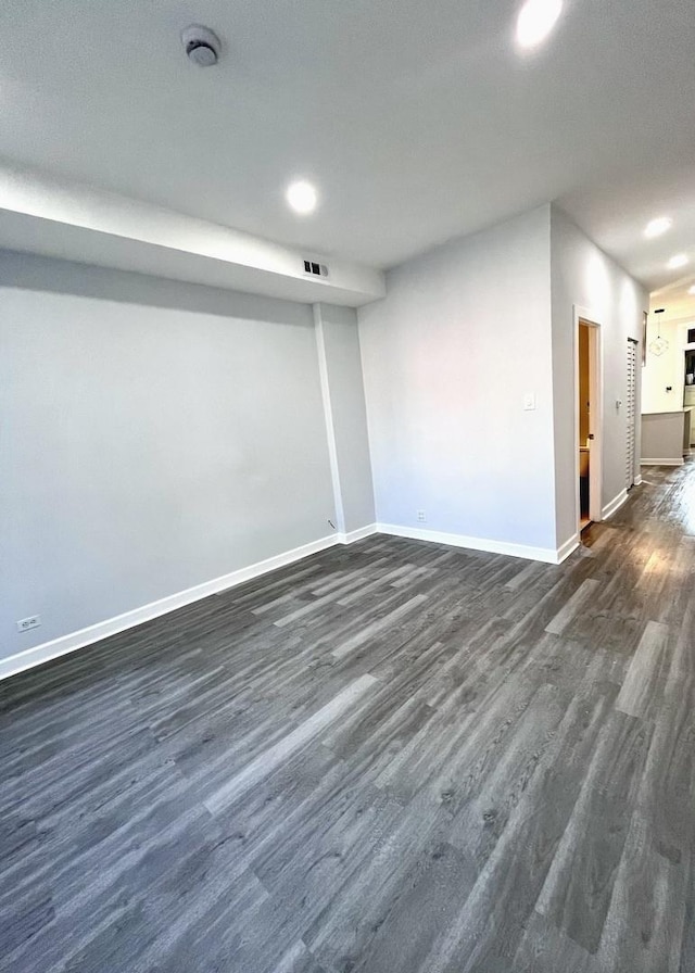 below grade area featuring baseboards, visible vents, and dark wood finished floors