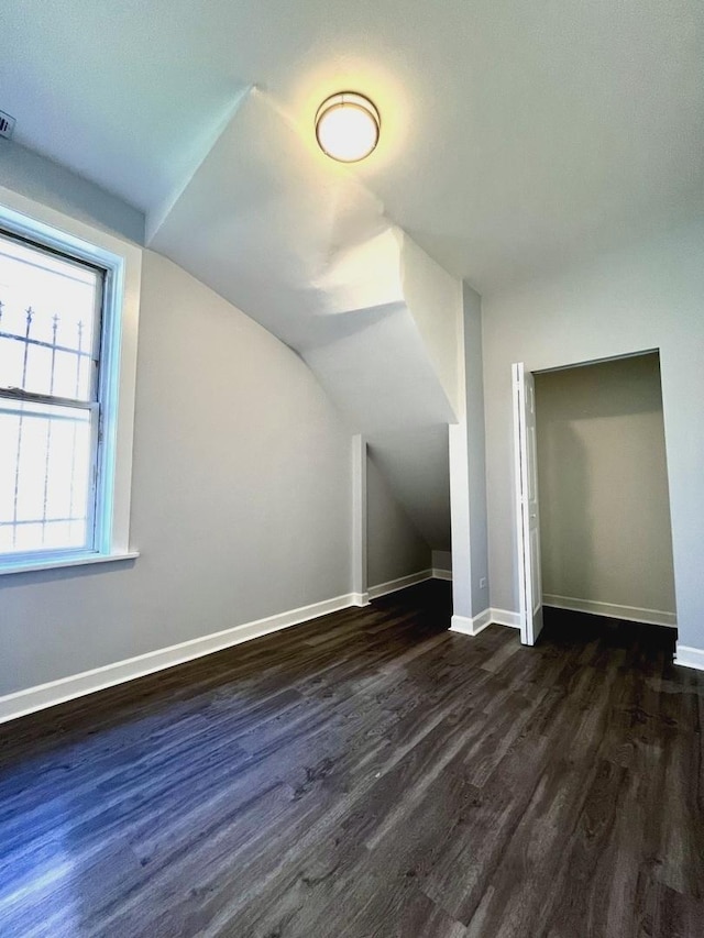 additional living space with lofted ceiling, dark wood-style floors, visible vents, and baseboards