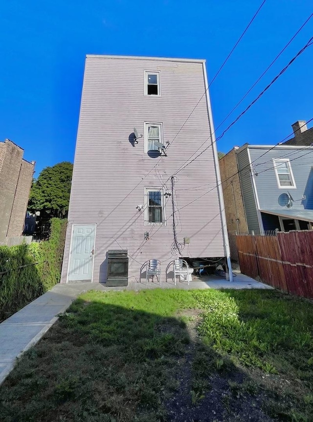 rear view of property with a lawn and fence