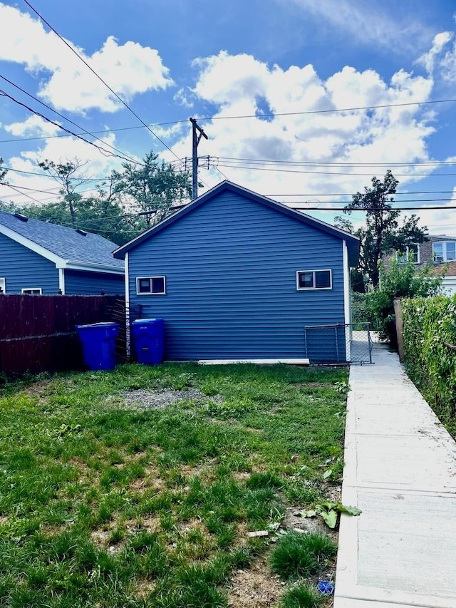 view of side of home with fence and a lawn