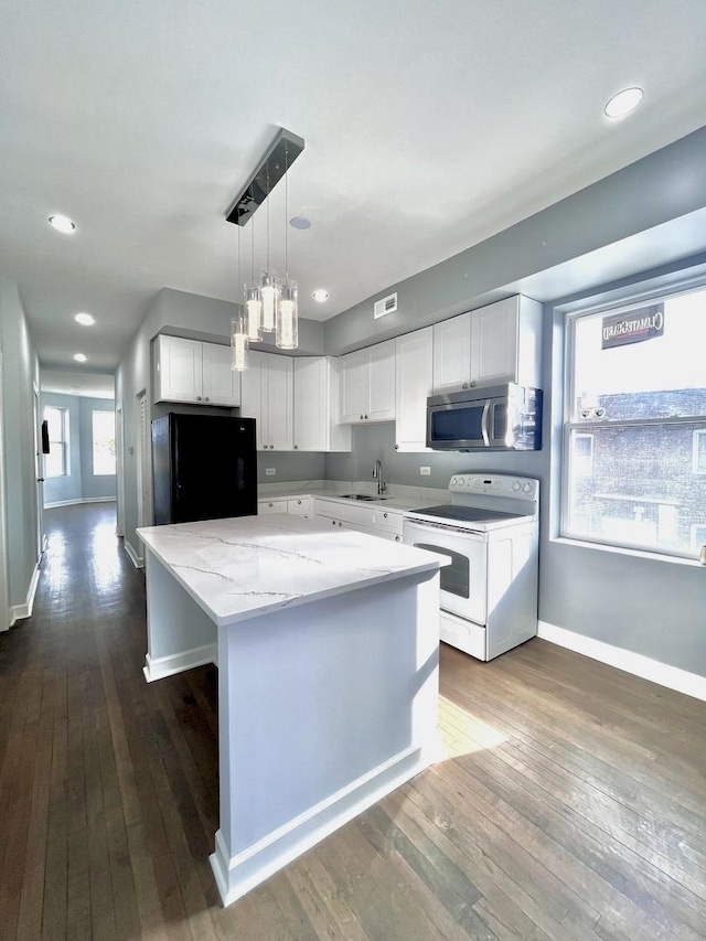 kitchen featuring a kitchen island, stainless steel microwave, black refrigerator, white electric range, and a sink