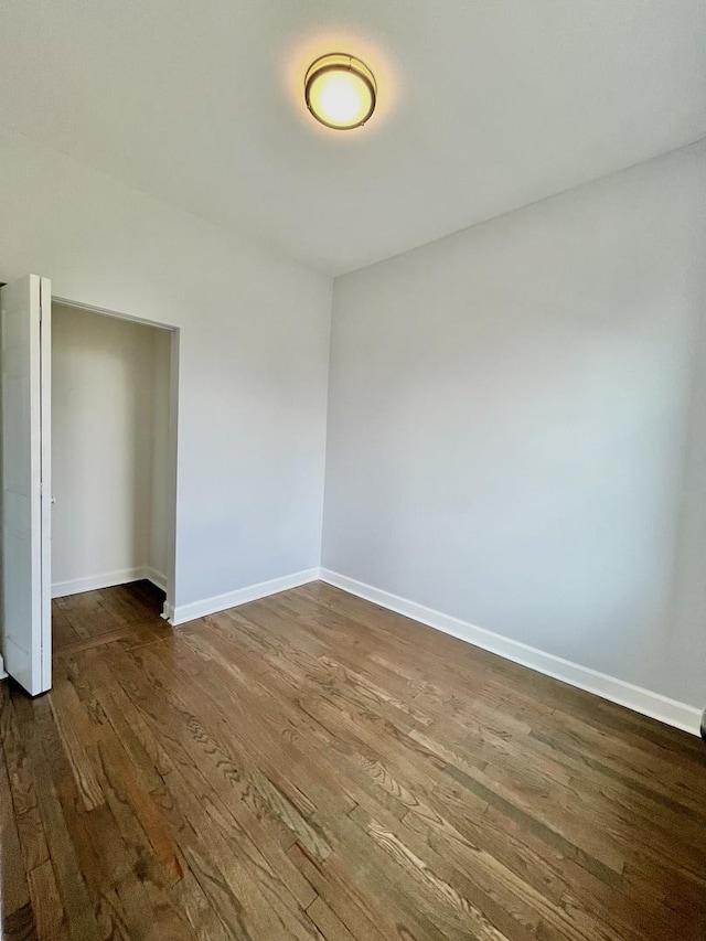 spare room featuring dark wood-style flooring and baseboards