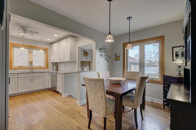 dining area featuring light wood finished floors, baseboards, a ceiling fan, and a wealth of natural light