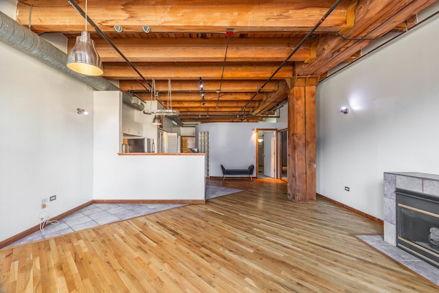 basement with baseboards, wood finished floors, a tiled fireplace, and freestanding refrigerator