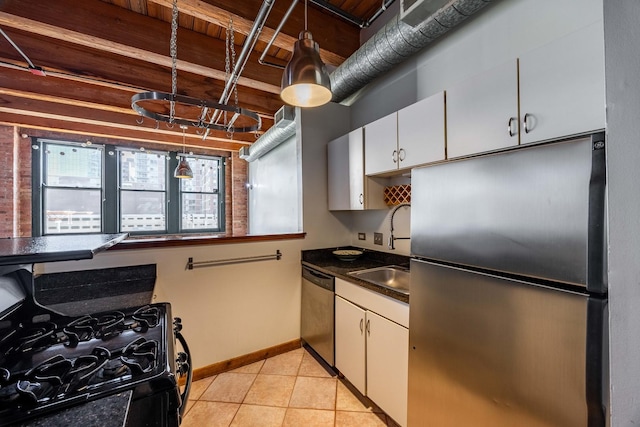 kitchen featuring dark countertops, appliances with stainless steel finishes, white cabinets, light tile patterned flooring, and baseboards