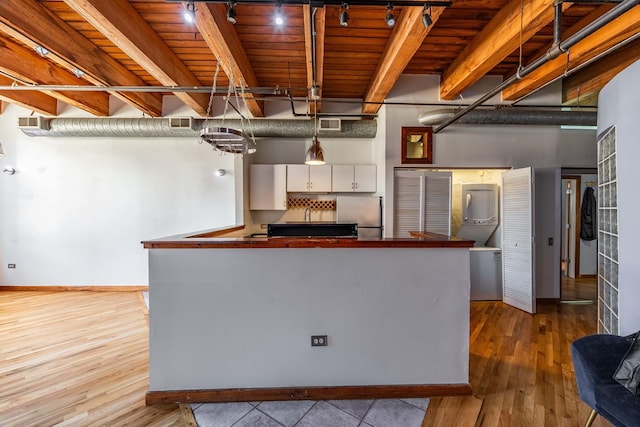 kitchen featuring beamed ceiling, wood finished floors, freestanding refrigerator, and white cabinets