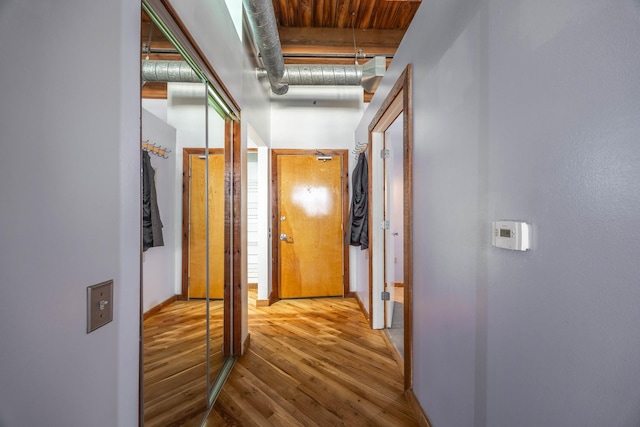 hallway with a towering ceiling, baseboards, and wood finished floors