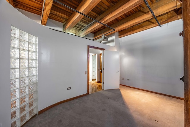 carpeted spare room with baseboards and beam ceiling