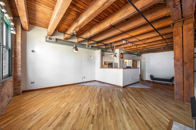 unfurnished living room with visible vents, baseboards, wood finished floors, and beamed ceiling