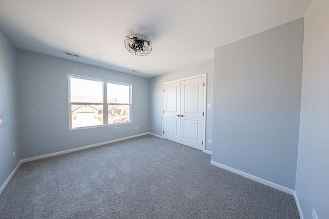 unfurnished bedroom featuring a closet, carpet flooring, visible vents, and baseboards