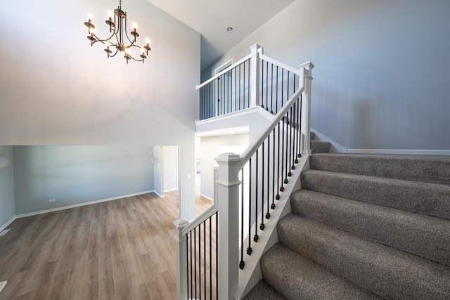 stairs with a high ceiling, an inviting chandelier, wood finished floors, and baseboards