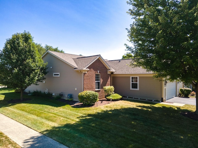 ranch-style home featuring an attached garage, roof with shingles, a front lawn, and brick siding