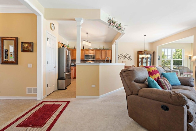 living room with light colored carpet, a notable chandelier, visible vents, baseboards, and ornate columns