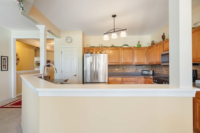 kitchen with decorative columns, decorative backsplash, appliances with stainless steel finishes, light carpet, and a sink