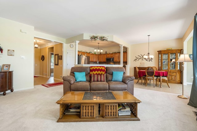 living area with light carpet, a notable chandelier, baseboards, and decorative columns