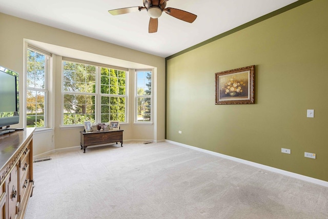 empty room with light colored carpet, ceiling fan, and baseboards