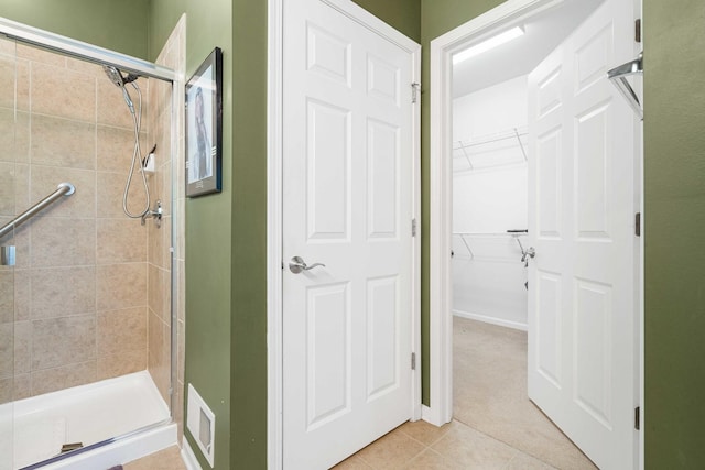 bathroom with a stall shower, a spacious closet, visible vents, and tile patterned floors