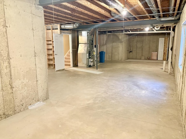 unfinished below grade area featuring stairway and heating unit