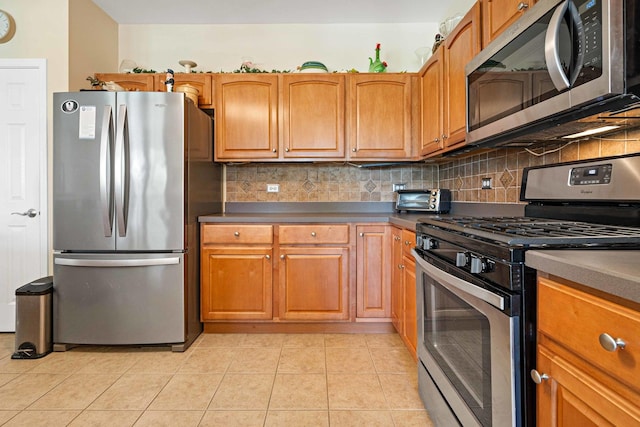 kitchen featuring appliances with stainless steel finishes, light tile patterned flooring, backsplash, and brown cabinets