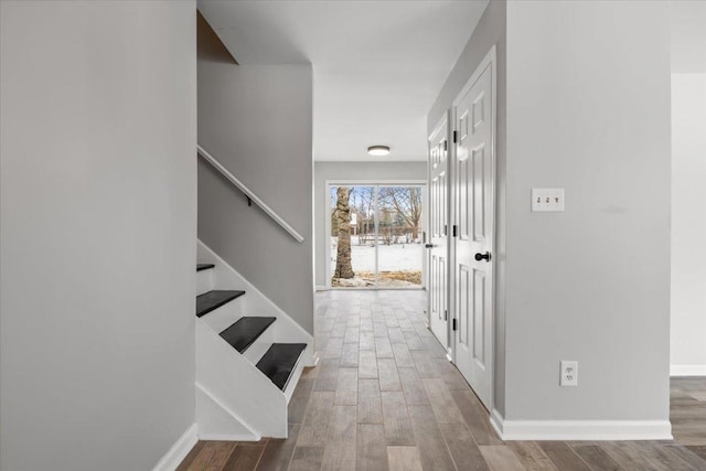 corridor with stairway, wood finished floors, and baseboards