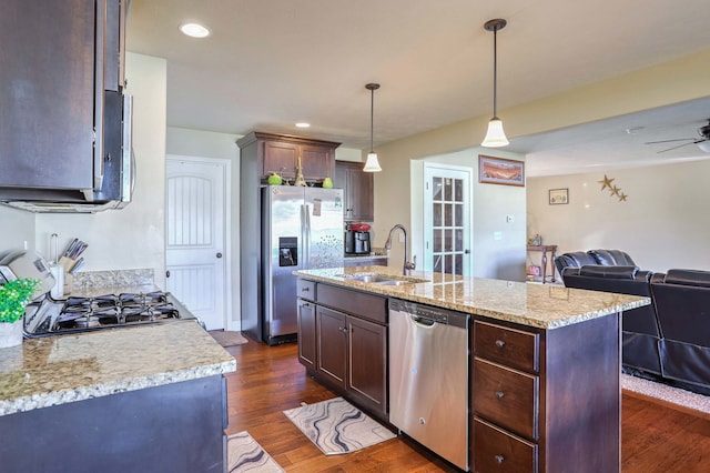 kitchen featuring dark wood finished floors, stainless steel appliances, open floor plan, a sink, and dark brown cabinets