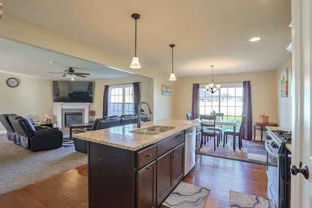 kitchen featuring dark brown cabinetry, a glass covered fireplace, a sink, stainless steel appliances, and a wealth of natural light