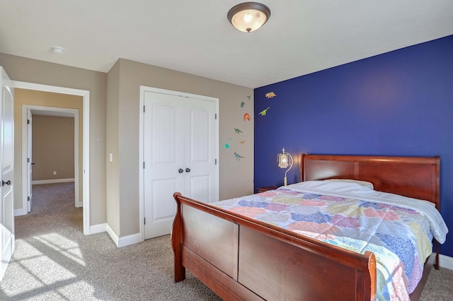 carpeted bedroom with a closet and baseboards