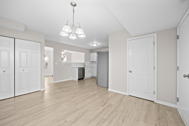 unfurnished living room featuring ceiling fan with notable chandelier, light wood finished floors, and baseboards