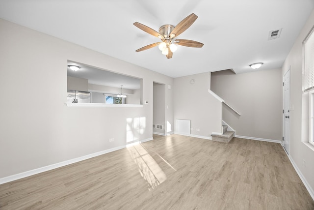 unfurnished living room featuring baseboards, visible vents, ceiling fan, wood finished floors, and stairs