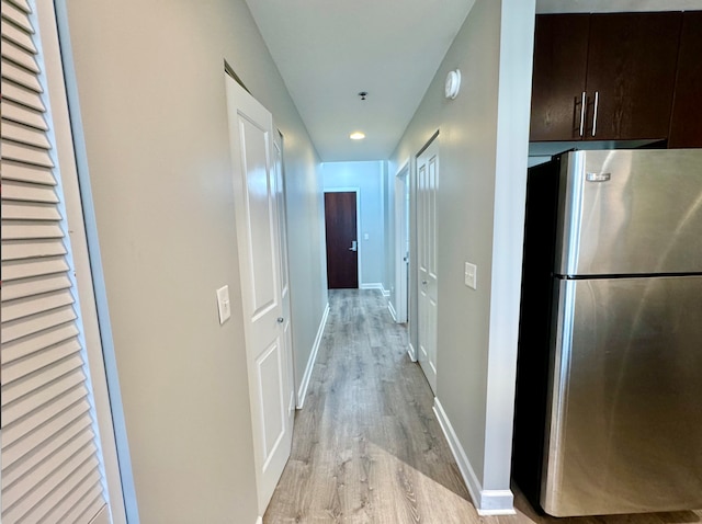 hallway featuring light wood-style flooring and baseboards