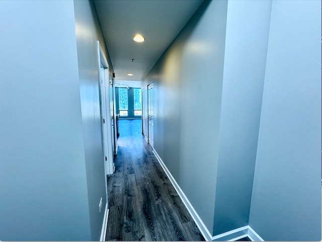 corridor featuring baseboards, dark wood-type flooring, and recessed lighting