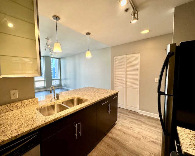 kitchen with freestanding refrigerator, a peninsula, stainless steel dishwasher, light wood-style floors, and a sink