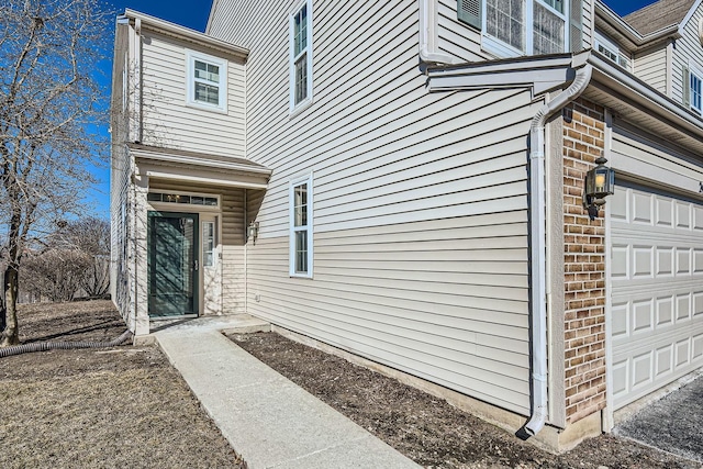 view of exterior entry featuring an attached garage and brick siding