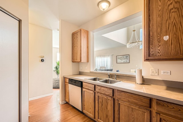 kitchen with brown cabinets, light countertops, a sink, light wood-type flooring, and dishwasher