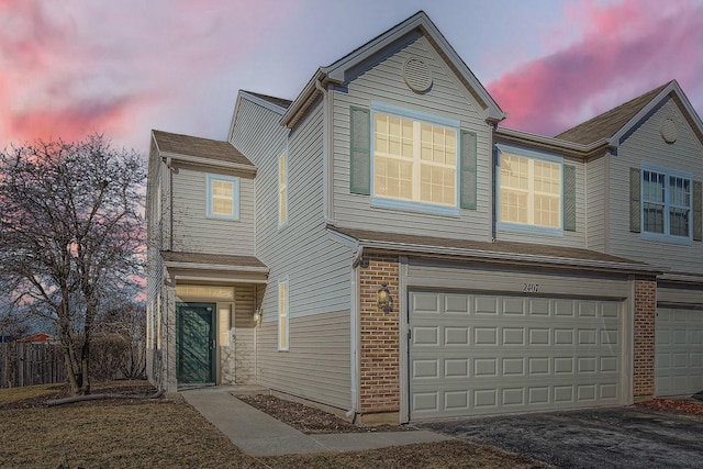 traditional-style home with a garage, brick siding, and aphalt driveway