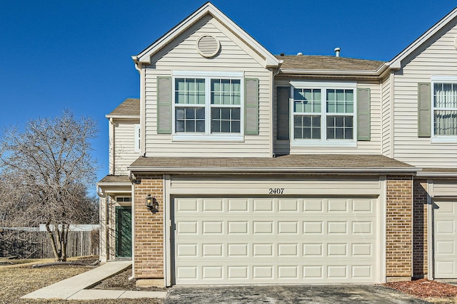 view of front of home with a garage, brick siding, driveway, and roof with shingles