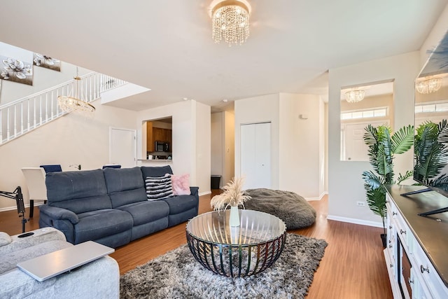 living area featuring a notable chandelier, baseboards, and wood finished floors