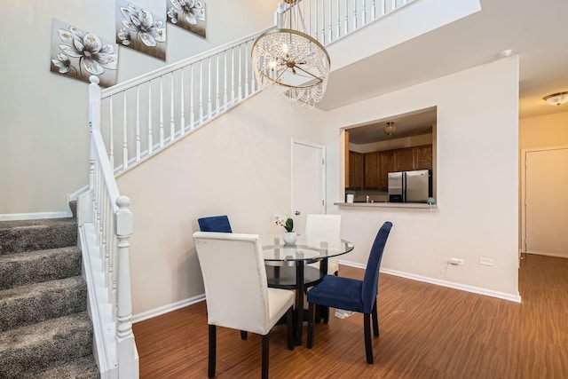 dining space featuring stairway, baseboards, a chandelier, and wood finished floors