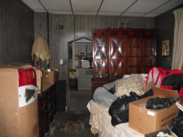 bedroom featuring wood walls and a paneled ceiling