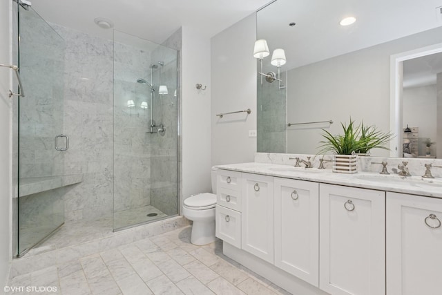 bathroom featuring double vanity, a stall shower, toilet, and a sink