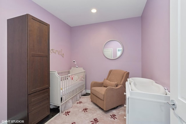 bedroom featuring recessed lighting, a crib, and light carpet