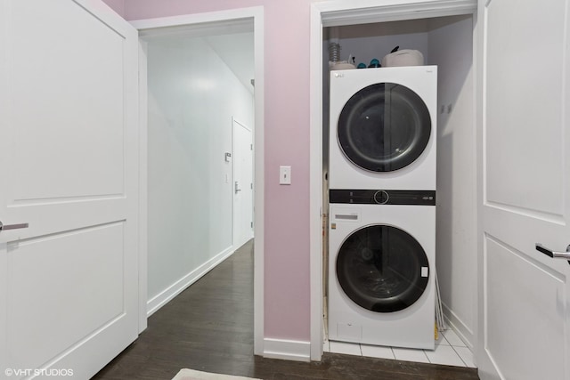 washroom featuring laundry area, stacked washer / drying machine, baseboards, and wood finished floors