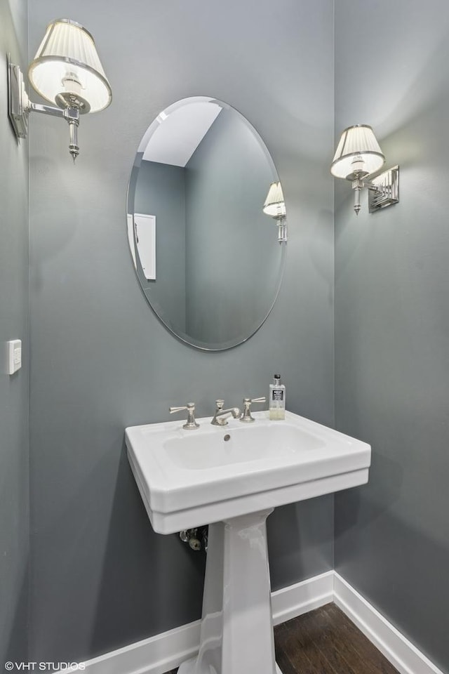 bathroom featuring wood finished floors, baseboards, and a sink