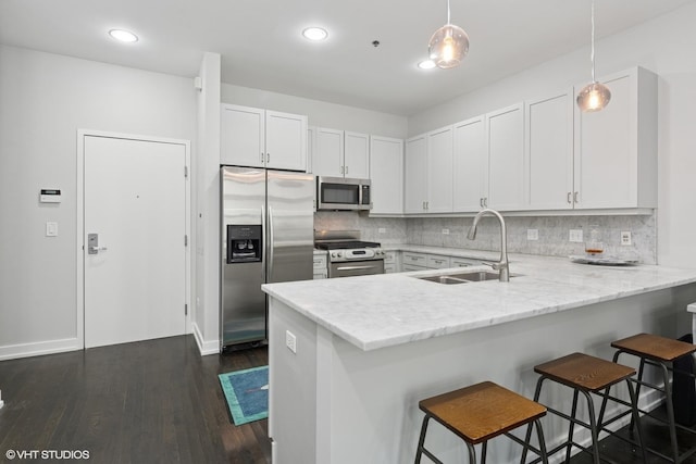 kitchen with a sink, tasteful backsplash, white cabinetry, stainless steel appliances, and a peninsula