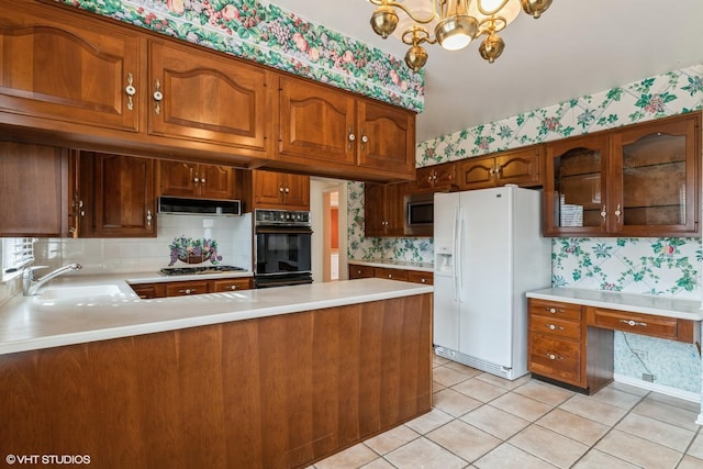 kitchen featuring appliances with stainless steel finishes, light countertops, a sink, and wallpapered walls